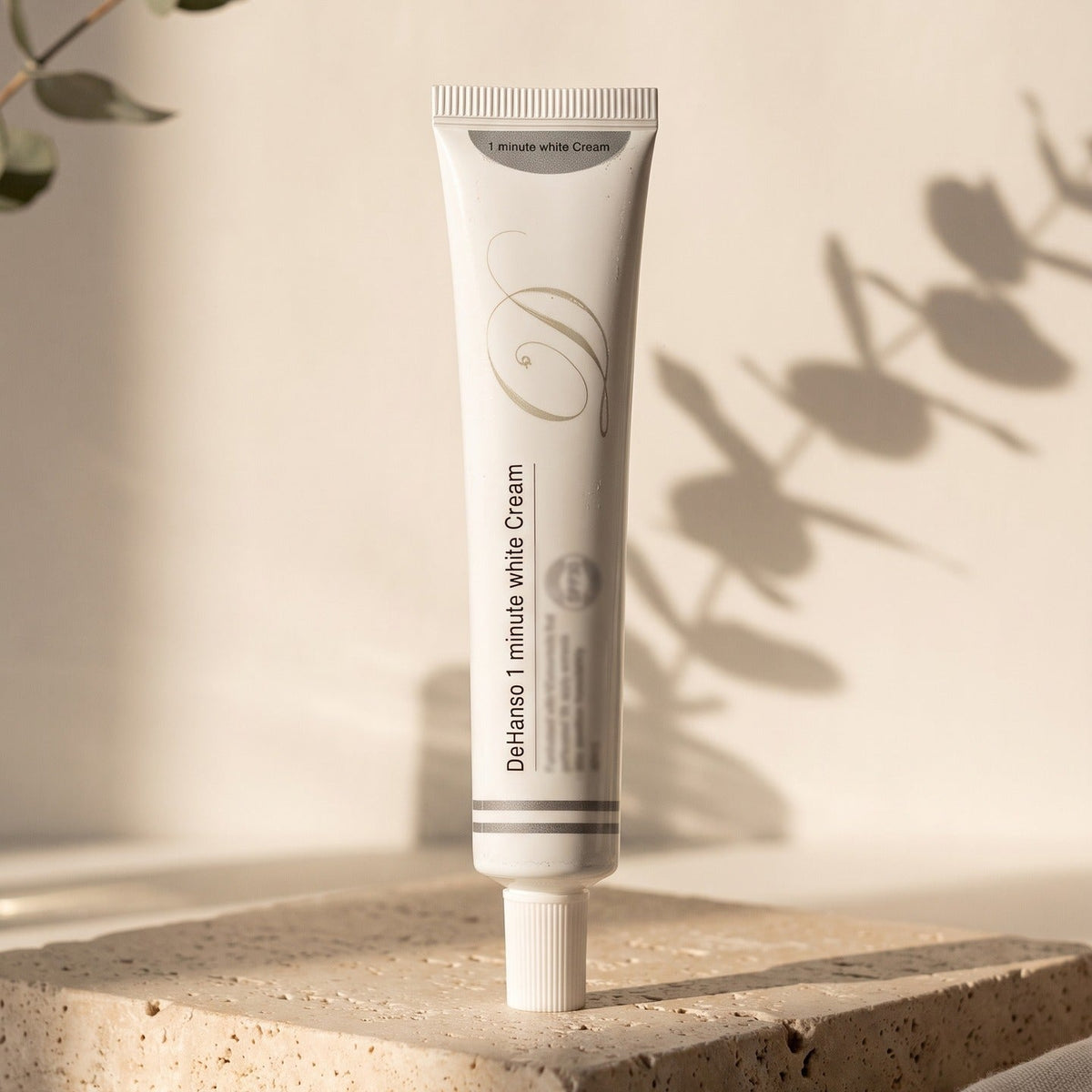 DeHanso 1 Minute White Cream tube on travertine stone with eucalyptus shadows